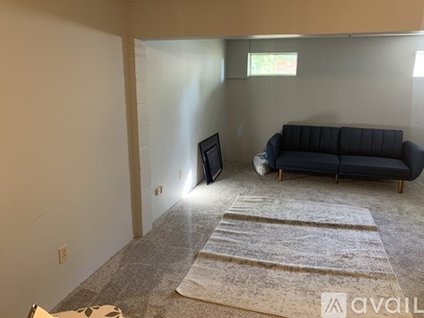 A living room with a blue couch and a rug.