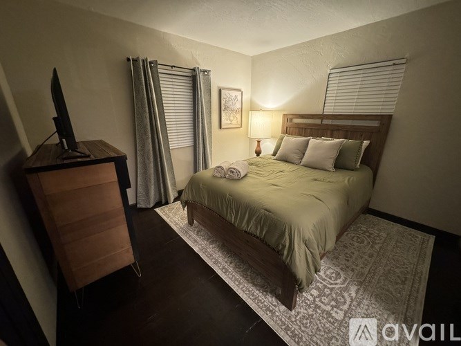 A bedroom with a bed, a dresser, and a window with curtains.