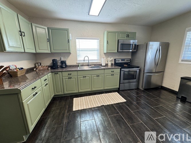 A kitchen with green cabinets and a black floor.