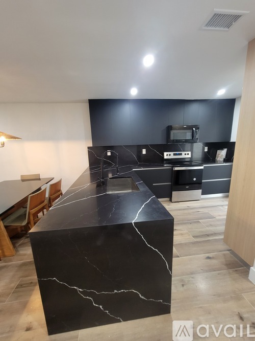 A kitchen with a black marble island in the middle.