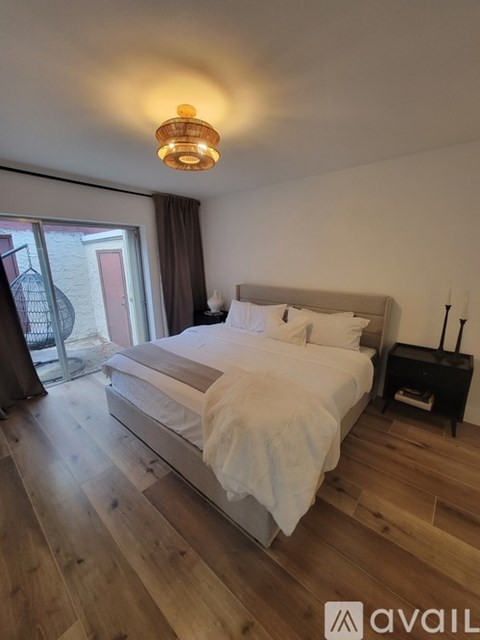 A bedroom with a large bed and wooden flooring.
