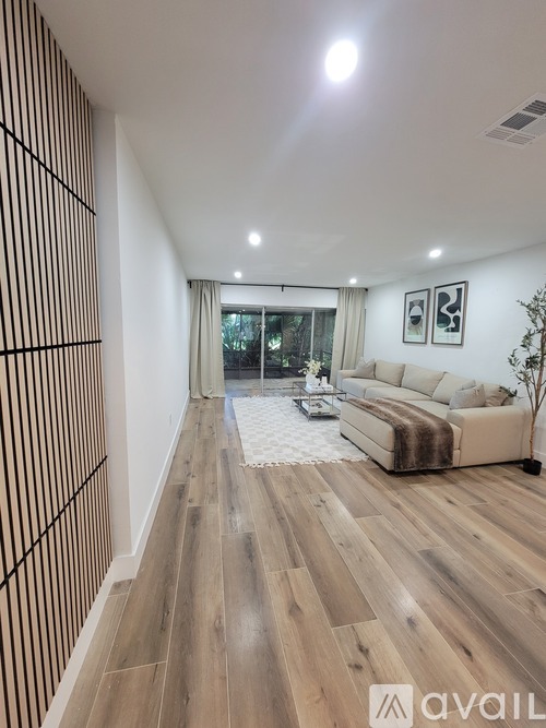 A living room with a couch, a rug, and a wall with a wooden panel design.