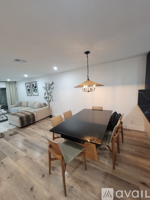 A modern dining room with a black table and wooden chairs.