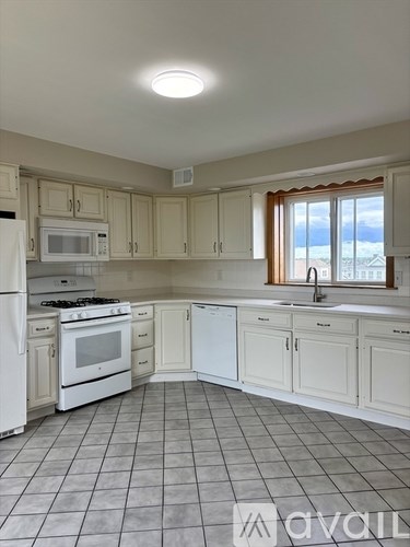 A kitchen with white appliances and cabinets.