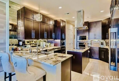 A modern kitchen with dark brown cabinets and a marble countertop.