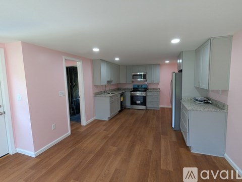 A kitchen with pink walls and wooden floors is available for rent.