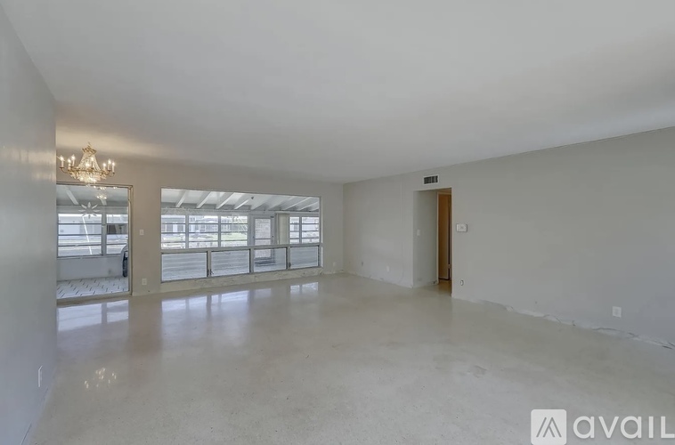 A spacious room with a mirror and a door leading to another room.