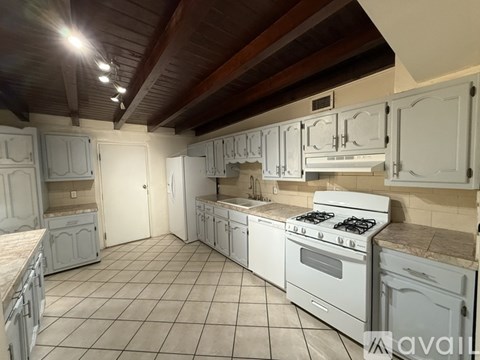 A kitchen with white cabinets and a white stove.