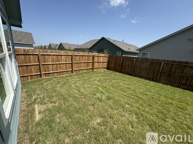 A backyard with a wooden fence and a green lawn.