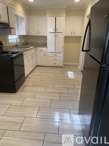 A kitchen with black appliances and white cabinets.