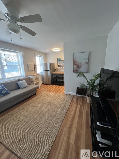 A living room with a grey couch and a brown rug.