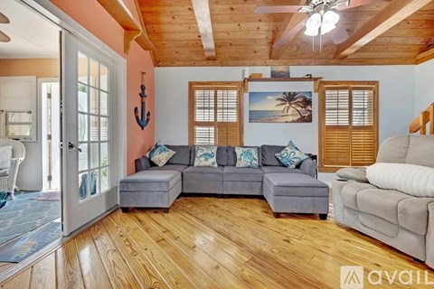A living room with a grey couch and wooden floors.