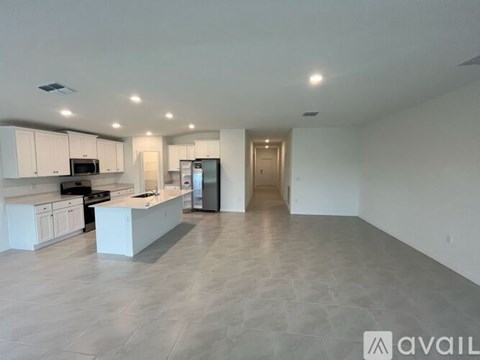 A spacious kitchen with white cabinets and appliances, a large island, and a tiled floor.