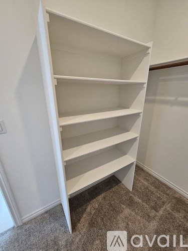A white shelving unit in a room with a carpeted floor.