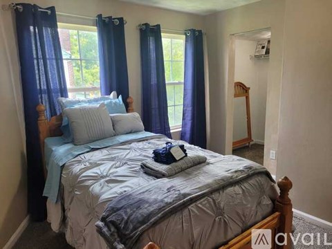 A bedroom with a bed, blue curtains, and a wooden headboard.