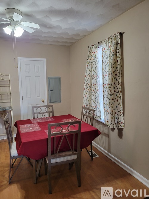 A dining room with a red tablecloth and chairs.