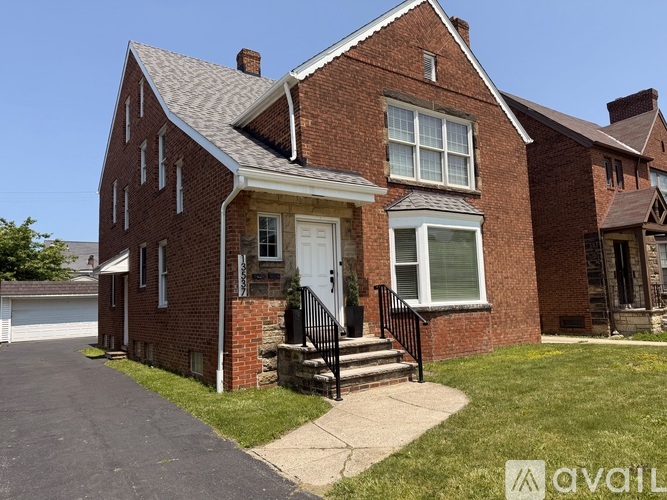 A red brick house with a white door and a black railing.