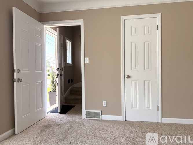 A room with two white doors, one of which is open, leading to a hallway.