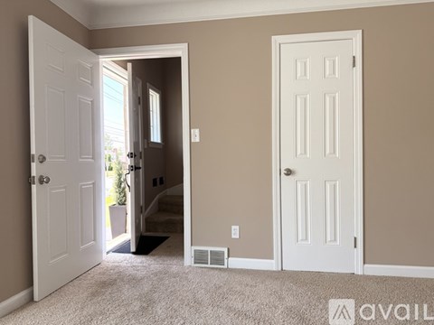 A room with two white doors, one of which is open, leading to a hallway.