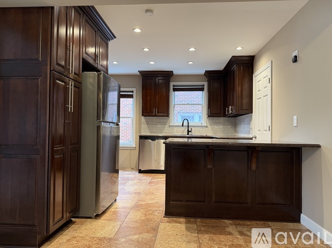 A kitchen with dark wood cabinets and a tiled floor.