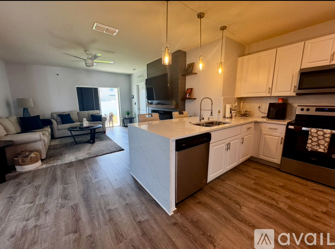 A modern kitchen with white cabinets and a wooden floor.