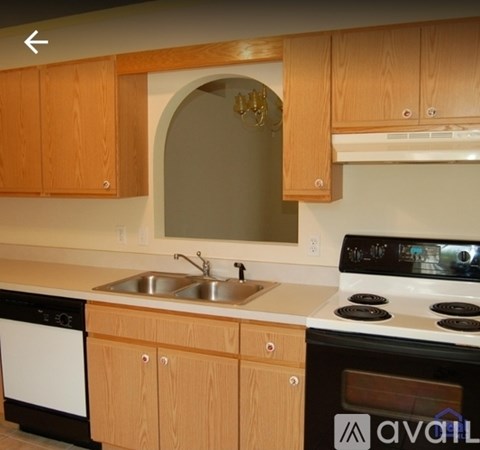 A kitchen with wooden cabinets and a white stove top oven.