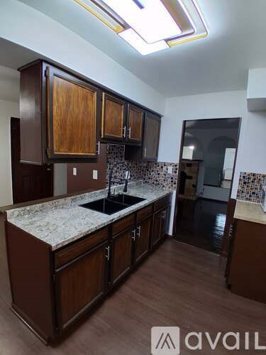 A kitchen with brown cabinets and a marble countertop.