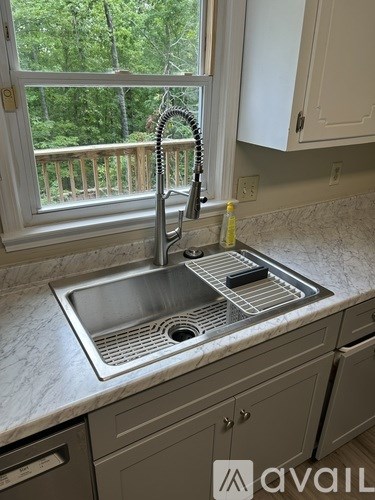 A kitchen sink with a faucet and a window in the background.