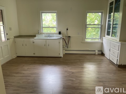 A kitchen with white cabinets and a wooden floor.