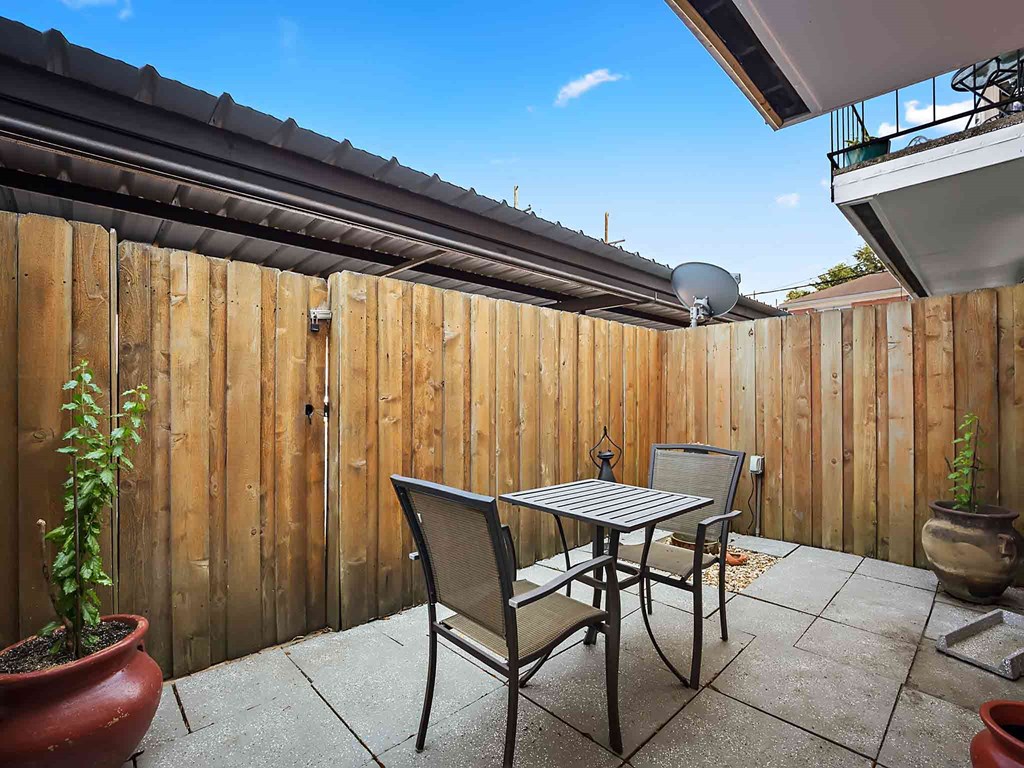 a patio with a table and chairs in front of a wooden fence