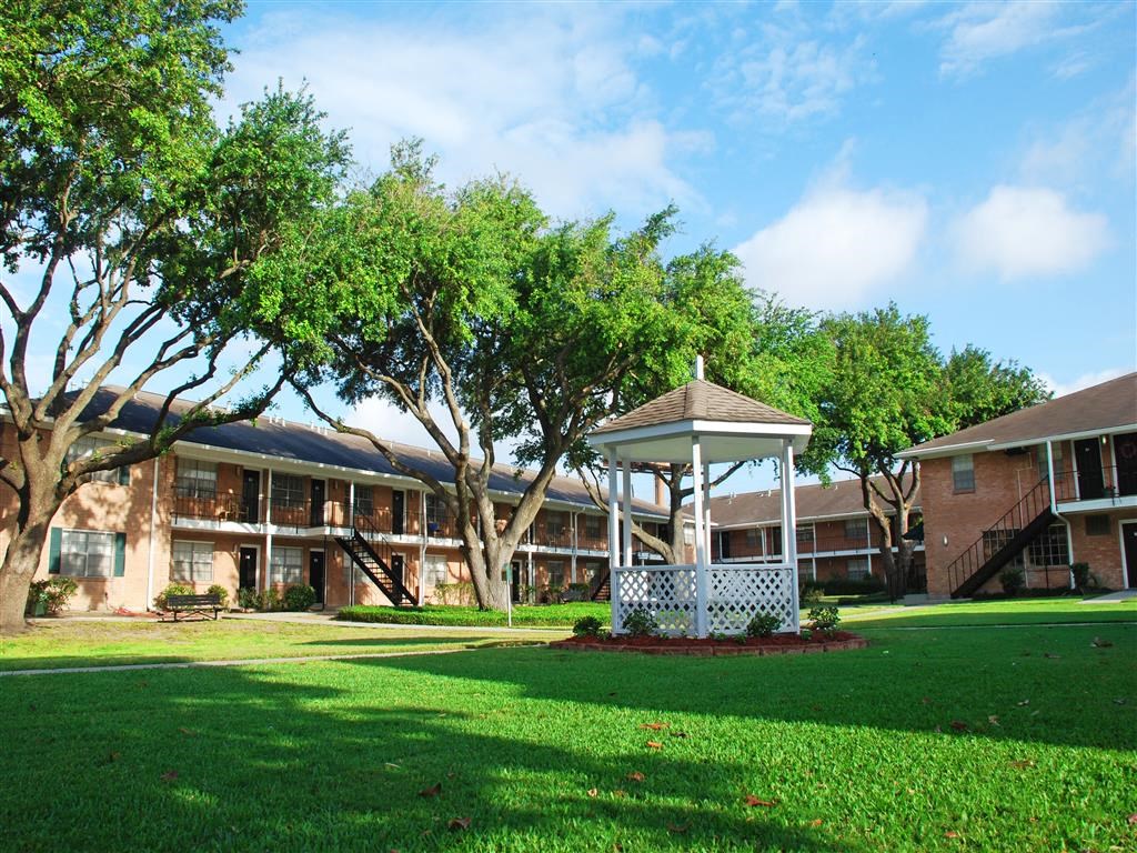 a gazebo in the middle of a yard in front of a building