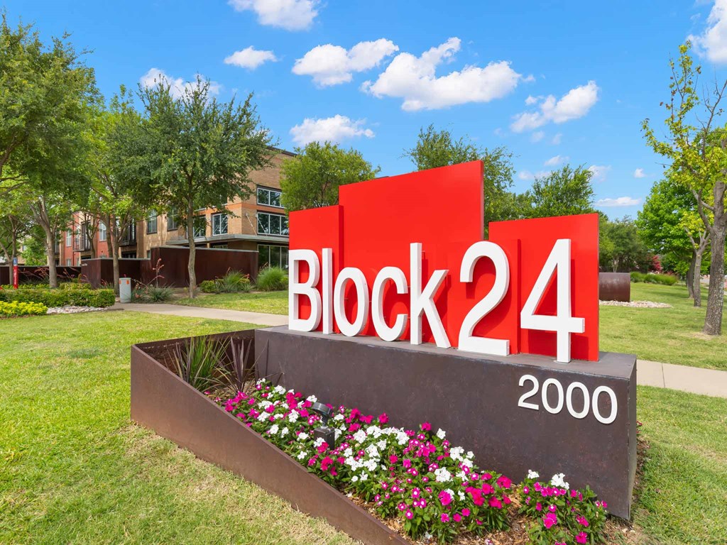 a sign for block 24 with flowers in front of a building
