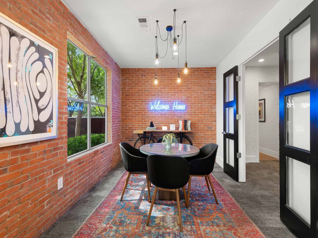 a dining room with a table and chairs in front of a brick wall