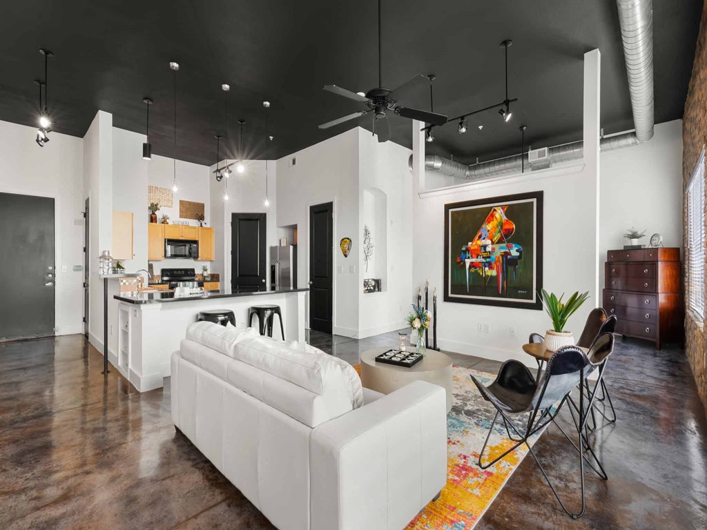 a large living room with a white couch and a kitchen