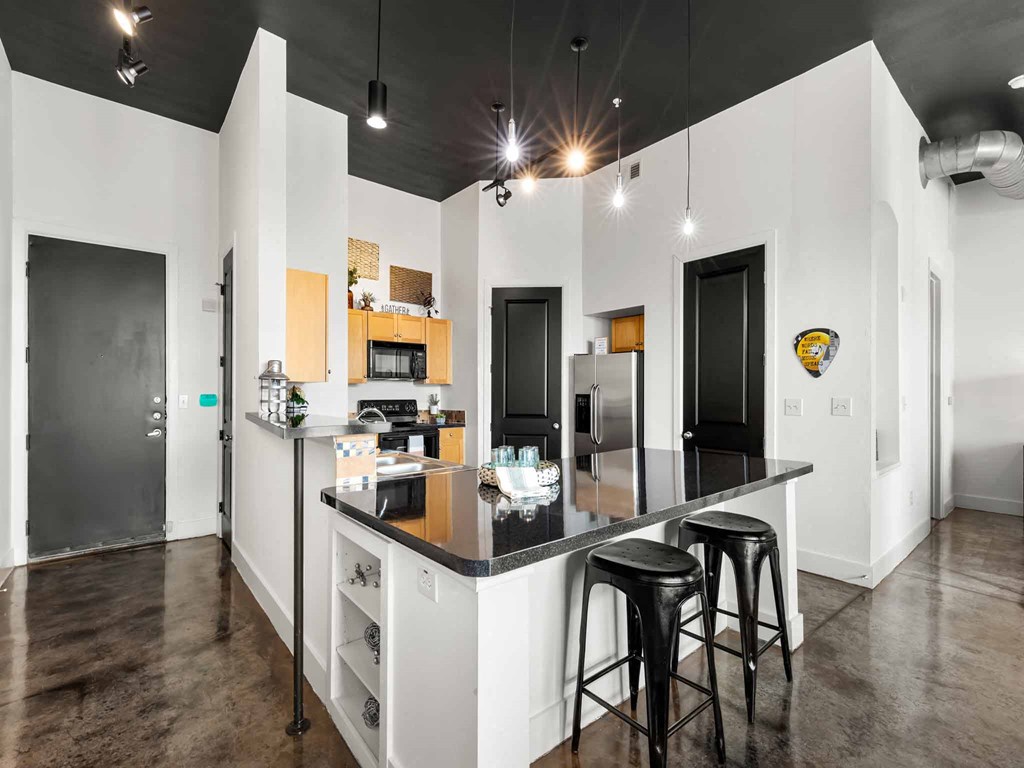 a kitchen with a counter and three stools in front of a counter top