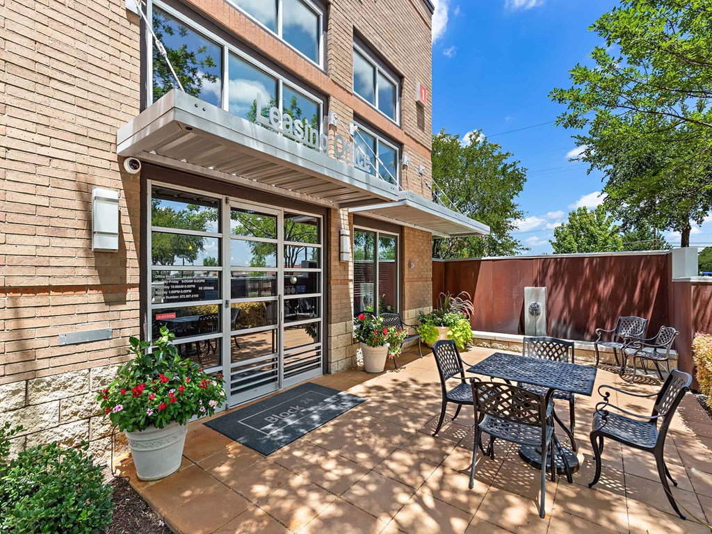 a patio with a table and chairs in front of a building