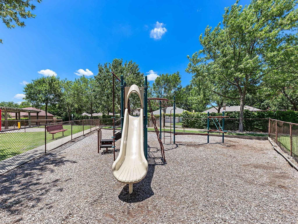 a playground with a slide and benches in a park
