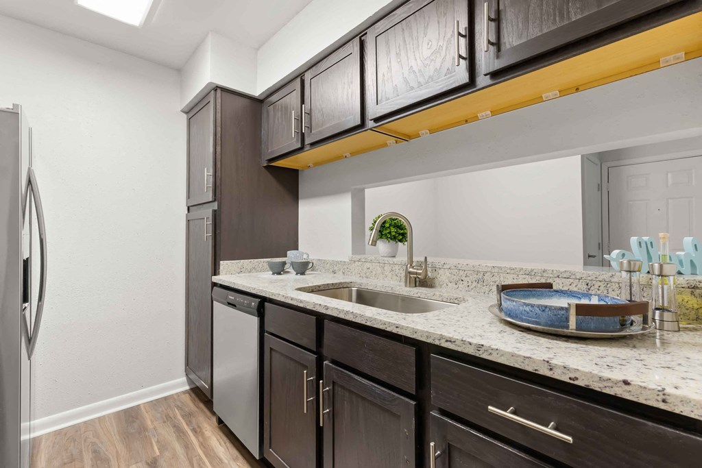 a kitchen with dark cabinets and a sink and a refrigerator