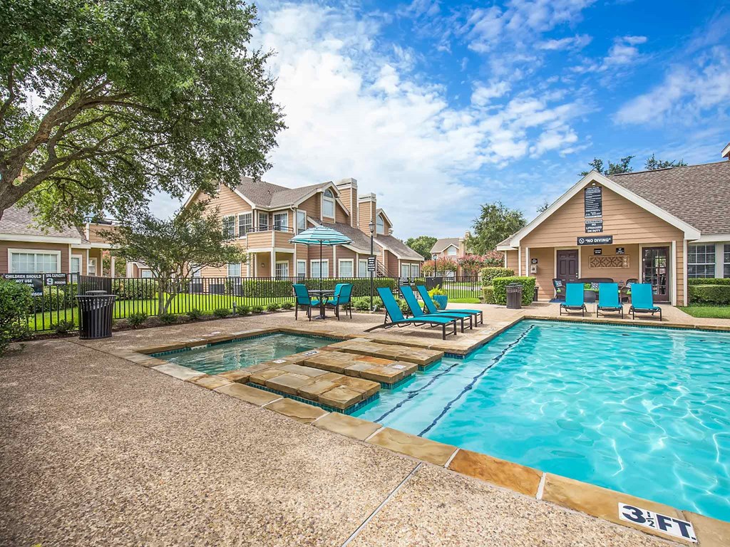 a swimming pool with blue chairs in front of a house