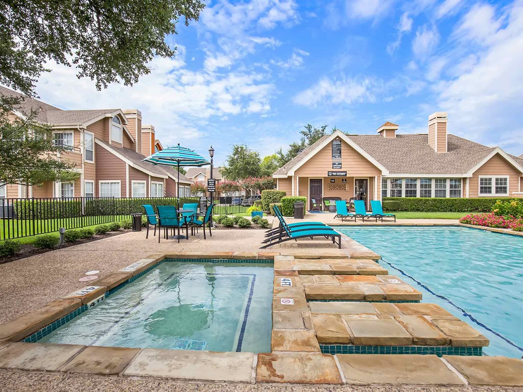 a swimming pool with chairs and umbrellas and houses in the background