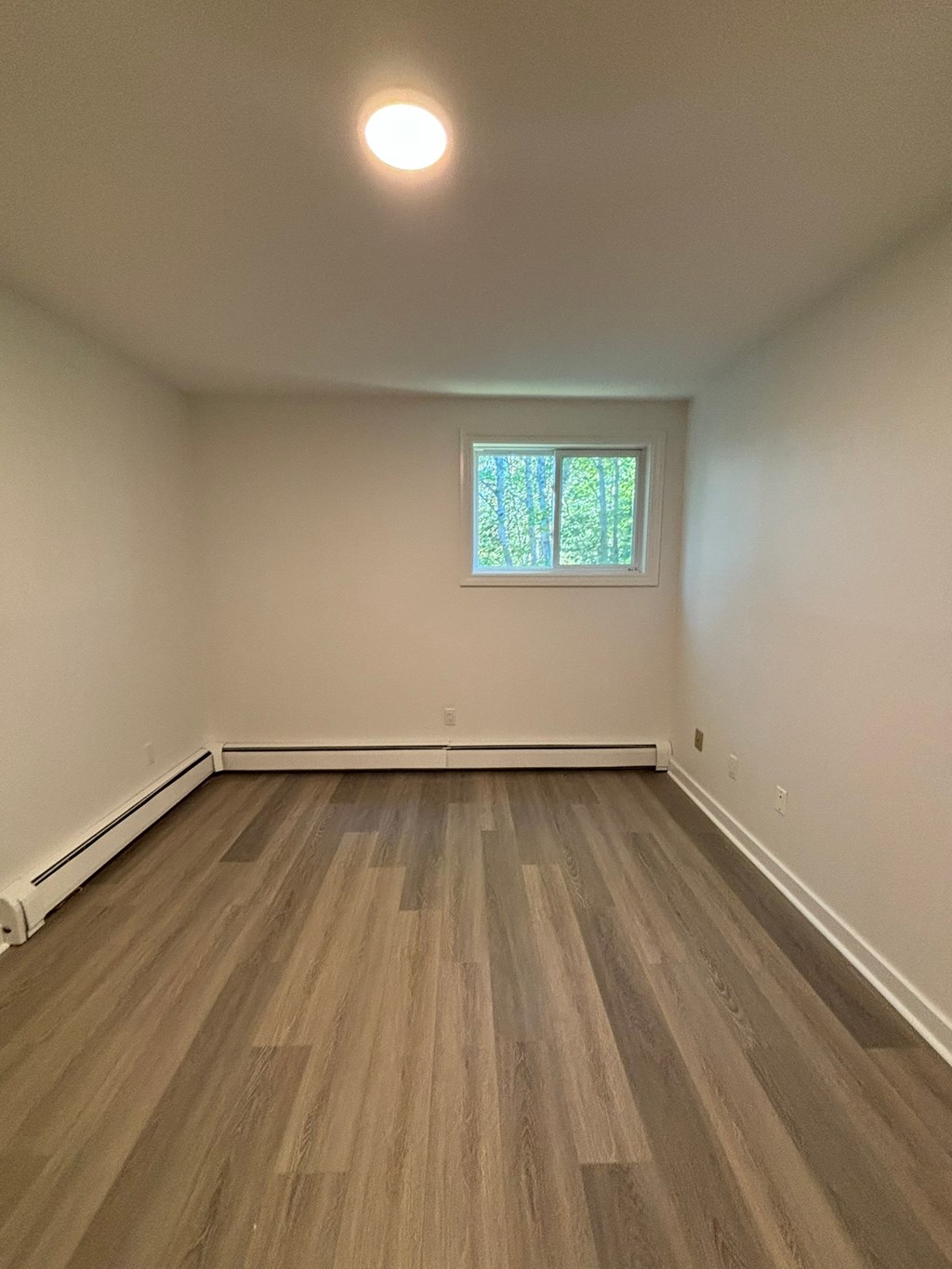 A room with a window and a wooden floor.