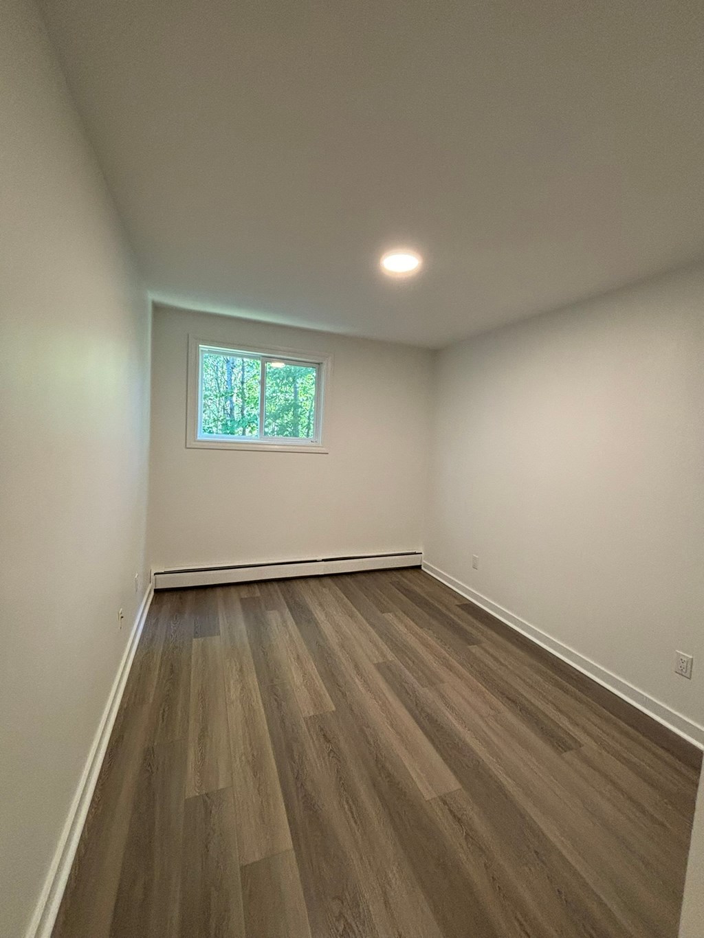 A room with wooden flooring and a window.