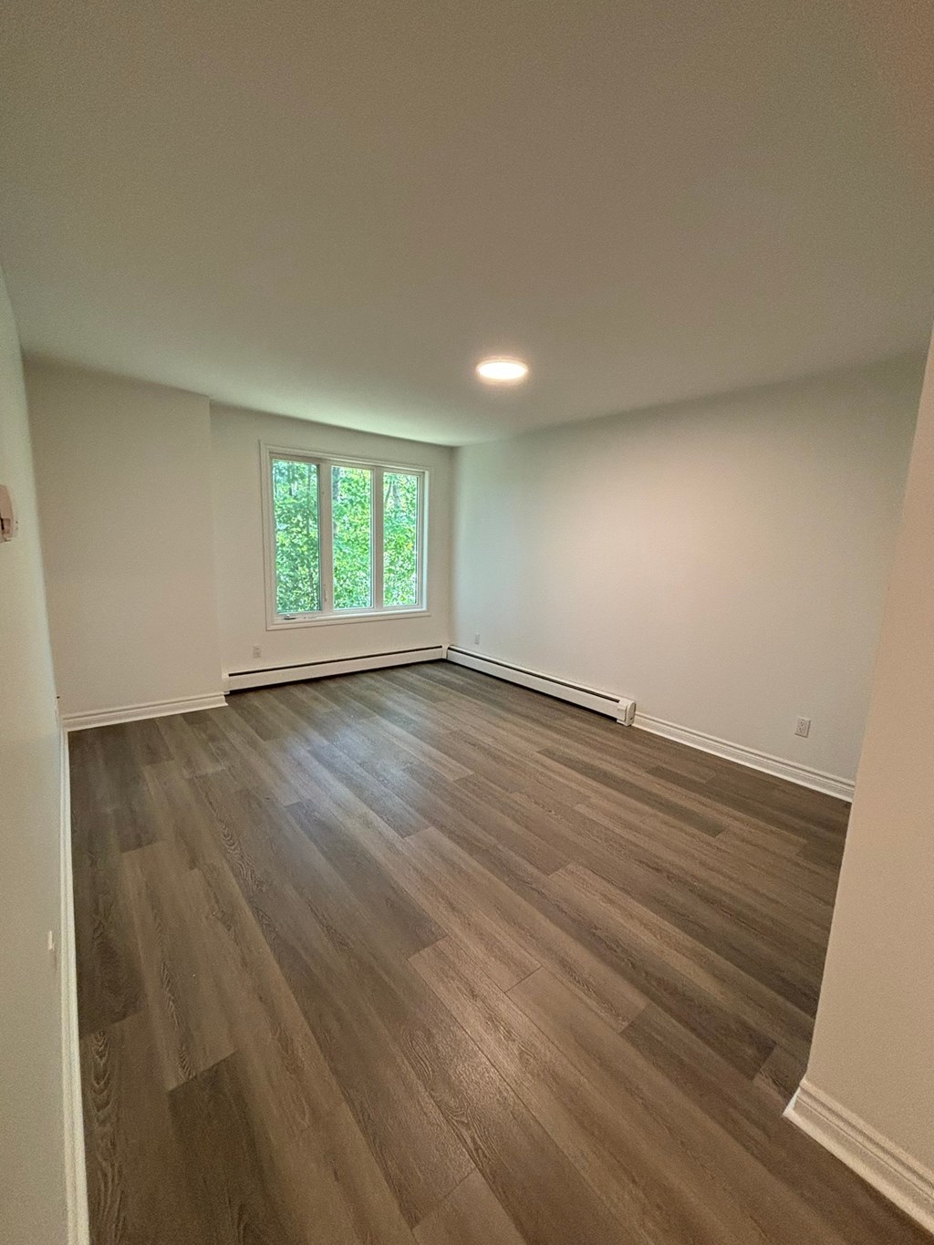 A room with wooden flooring and a window.