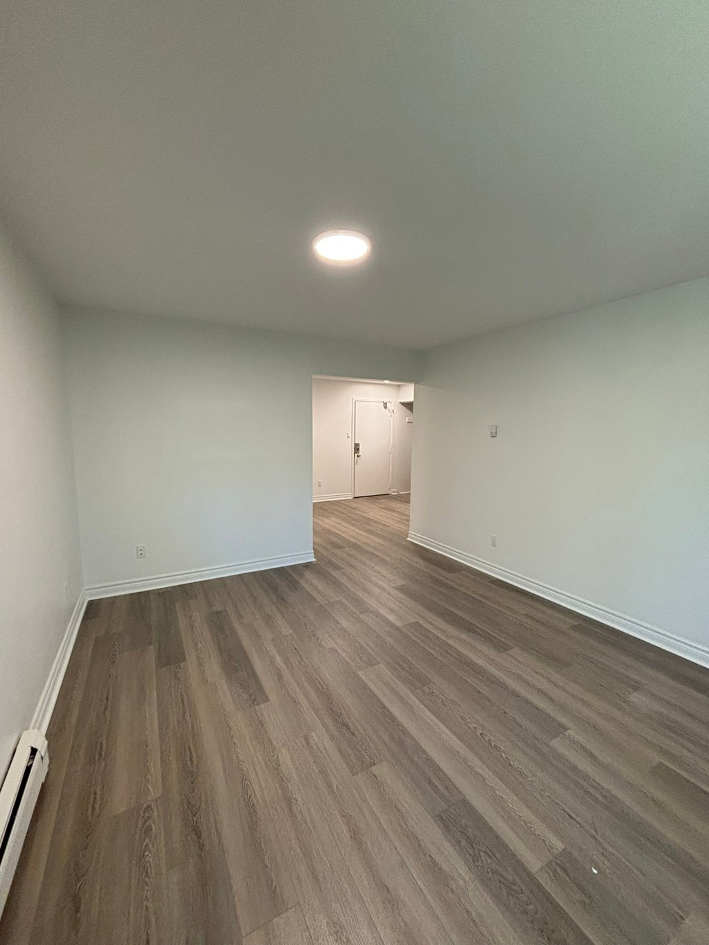 A room with a wooden floor and a white wall.