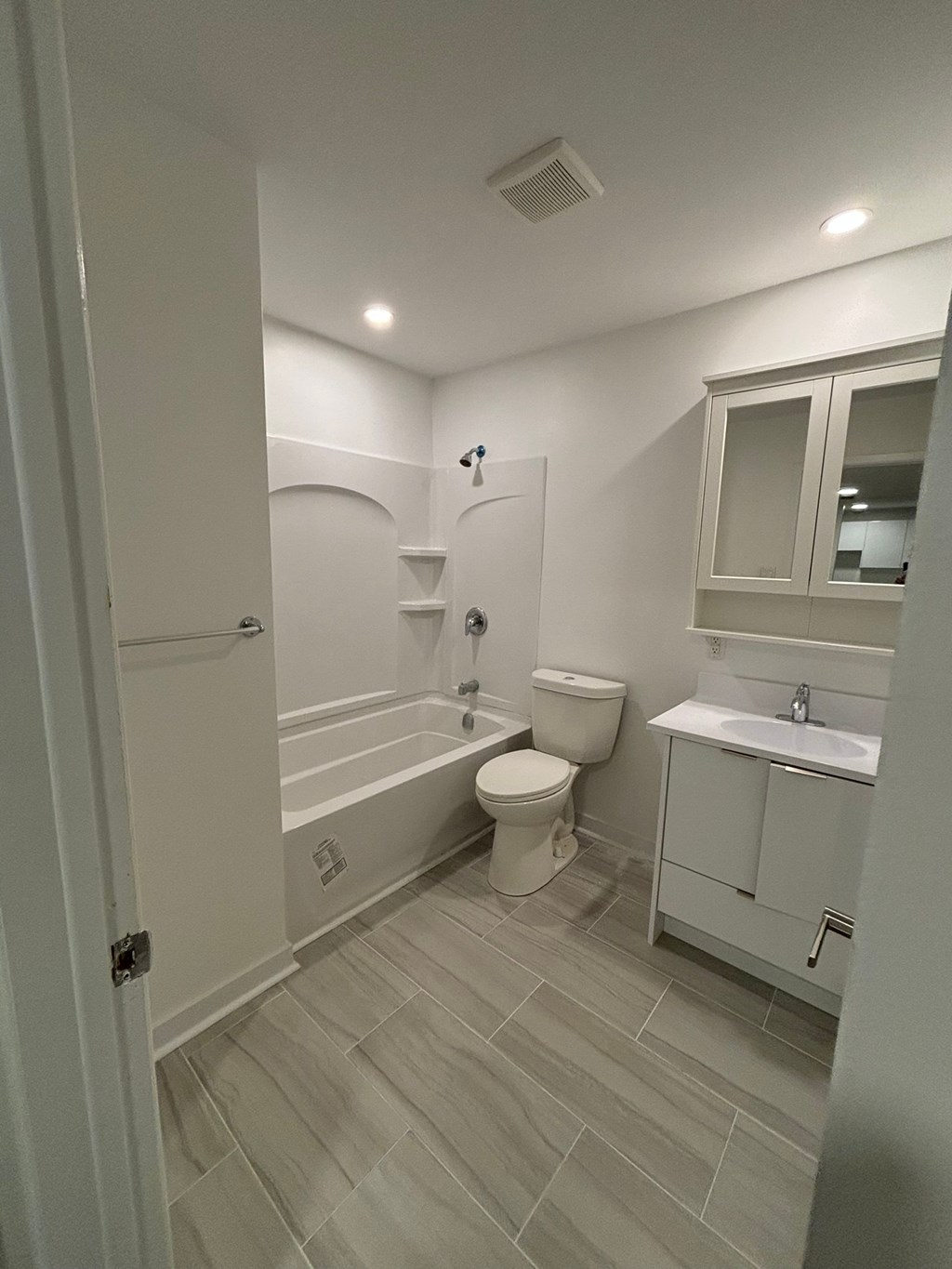 A white bathroom with a toilet, sink, and bathtub.