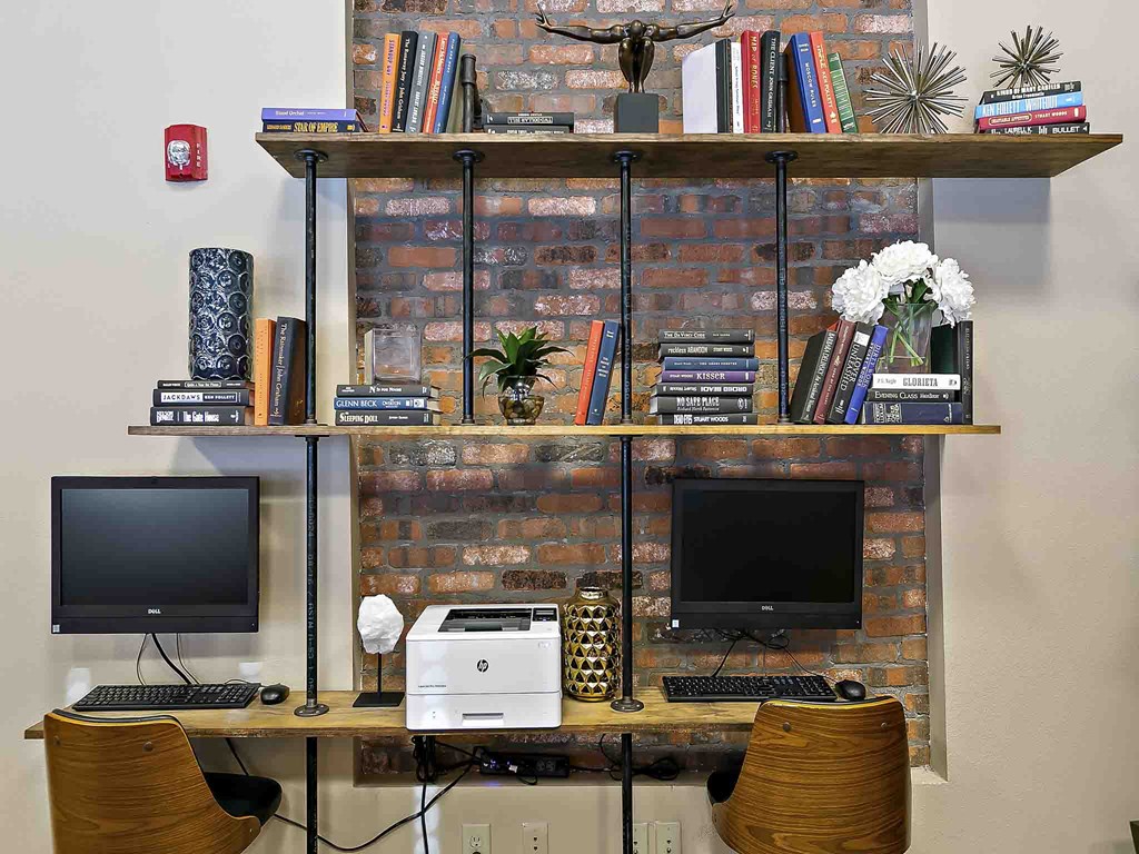 a desk with a computer and a shelf with books
