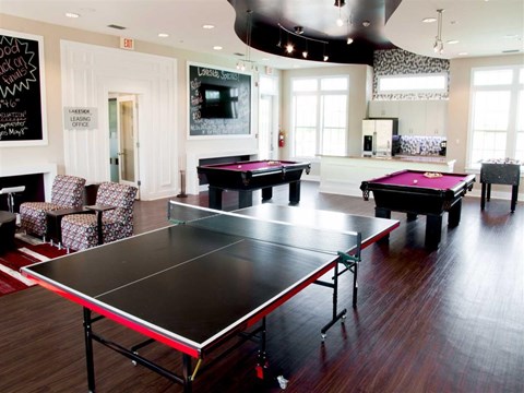 a game room with two pool tables and a tv