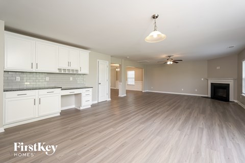 A spacious kitchen with white cabinets and a wooden floor.