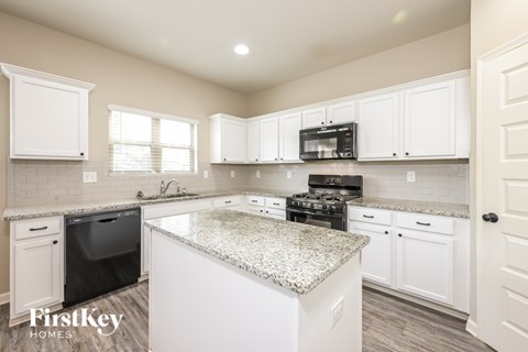 A kitchen with white cabinets and a granite countertop.