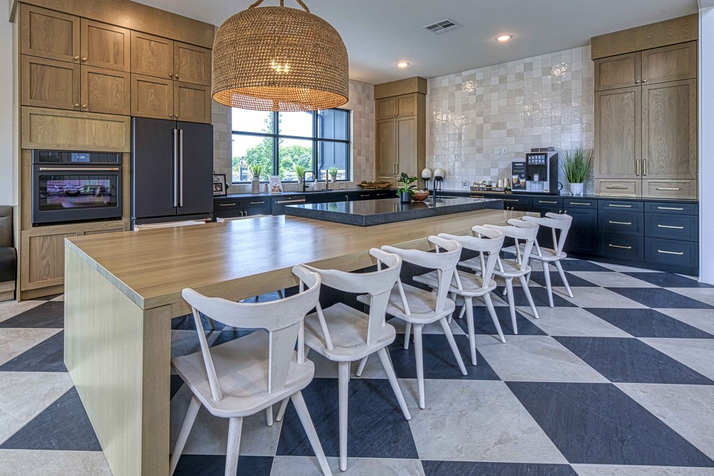 A kitchen with a checkered floor and a long table with chairs.